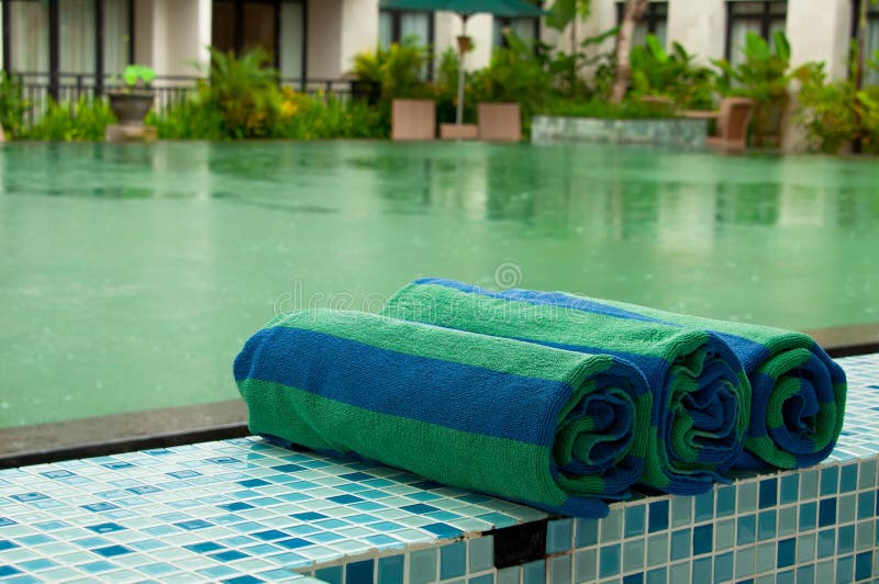 Roles of unused swimming pool towel with a pool background during rain. Roles of unused swimming pool towel with a pool background during rain
