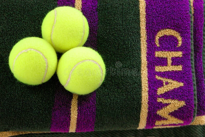 Three tennis balls on a purple and gold towel. Three tennis balls on a purple and gold towel