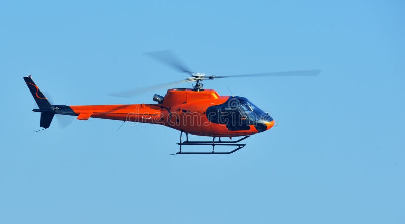 Orange helicopter flying against a clear blue sky. Panned with 1/125s shutter to show rotor's spinning. Orange helicopter flying against a clear blue sky. Panned with 1/125s shutter to show rotor's spinning.