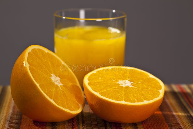 Glass of orange juice with 1 orang cut in 2 and blue background. Glass of orange juice with 1 orang cut in 2 and blue background