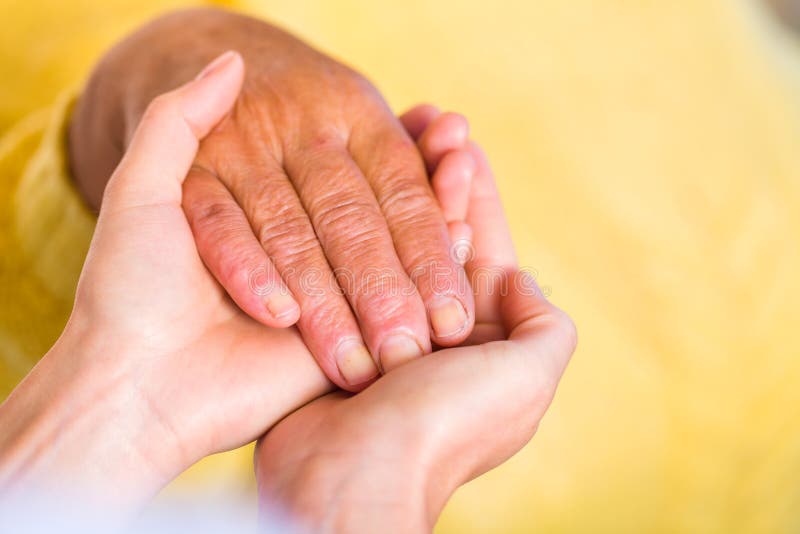 Close up photo of elderly woman hand hold by young carer hand. Close up photo of elderly woman hand hold by young carer hand