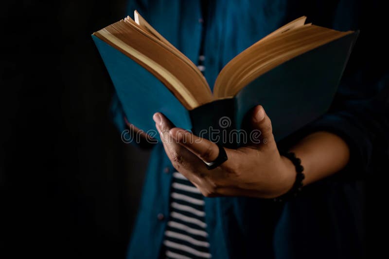 Понятие чтения Человек держит открытую библейскую книгу в руке Темный тон стоковое изображение rf