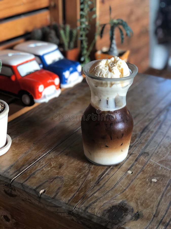 Поплавок latte льда, кофе льда покрыл с мороженым в стекле на винтажном деревянном столе стоковая фотография rf Поплавок latte льда, кофе льда покрыл с мороженым в стекле на винтажном деревянном столе стоковая фотография rf