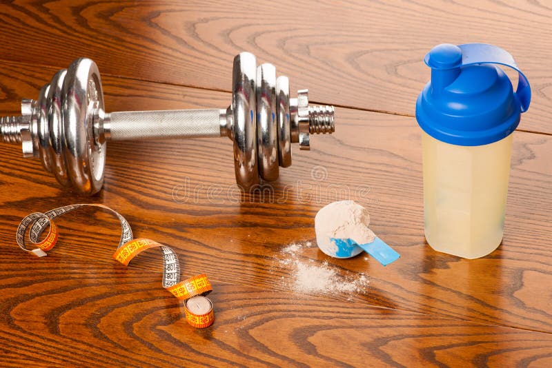 Порошок протеина Whey в ветроуловителе, гантели, ленте метра и пластмассе s стоковые фотографии rf Порошок протеина Whey в ветроуловителе, гантели, ленте метра и пластмассе s стоковые фотографии rf