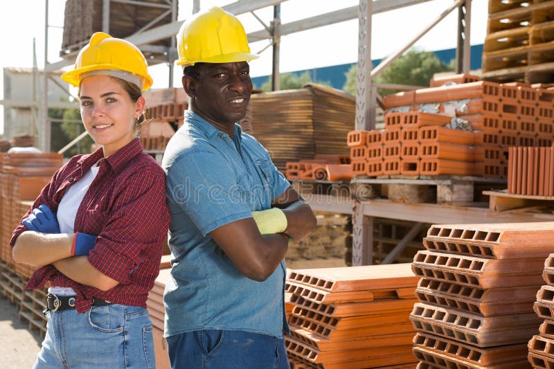 Portrait of two successful workers, african men and european woman, posing at a construction store outdoors. Portrait of two successful workers, african men and european woman, posing at a construction store outdoors