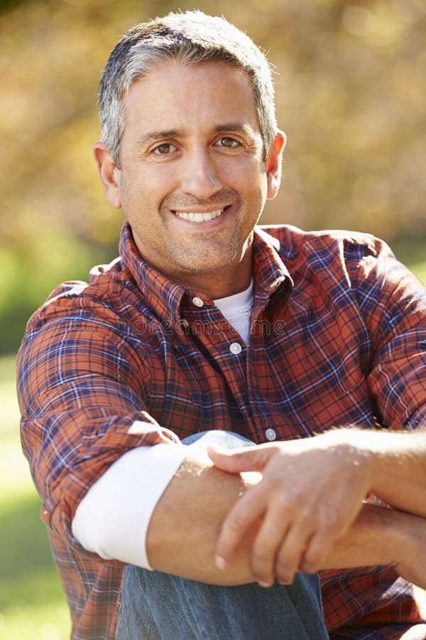 Portrait Of Hispanic Man In Countryside Smiling At Camera Whilst Sitting Down. Portrait Of Hispanic Man In Countryside Smiling At Camera Whilst Sitting Down