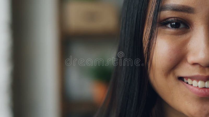 Портрет конца-вверх slowmotion стороны симпатичной азиатской дамы половинной с темным глазом, красивой кожей с составом и белизно