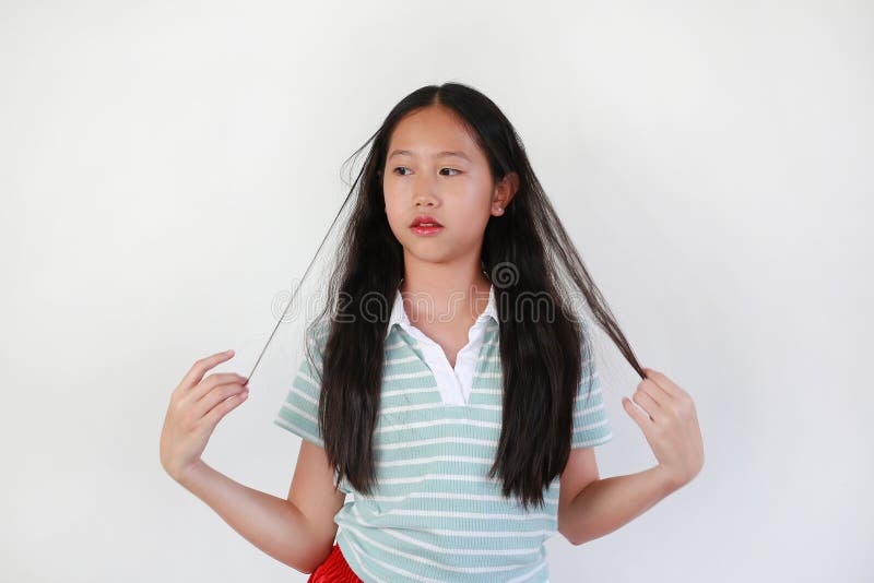 Портрет молодой азиатской девушки с длинными черными волосами, держа пряди волос в белой студии стоковые изображения