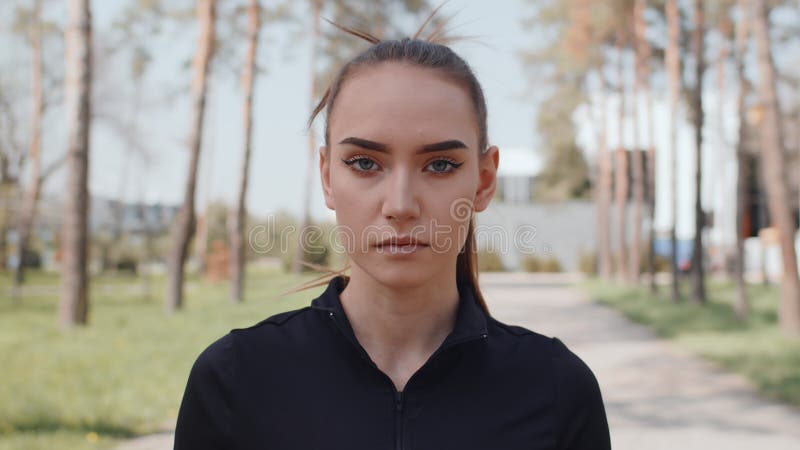 портрет молодой кавказской бегуньи, поднимающей голову и смотрящей в камеру перед спортивными тренировками в