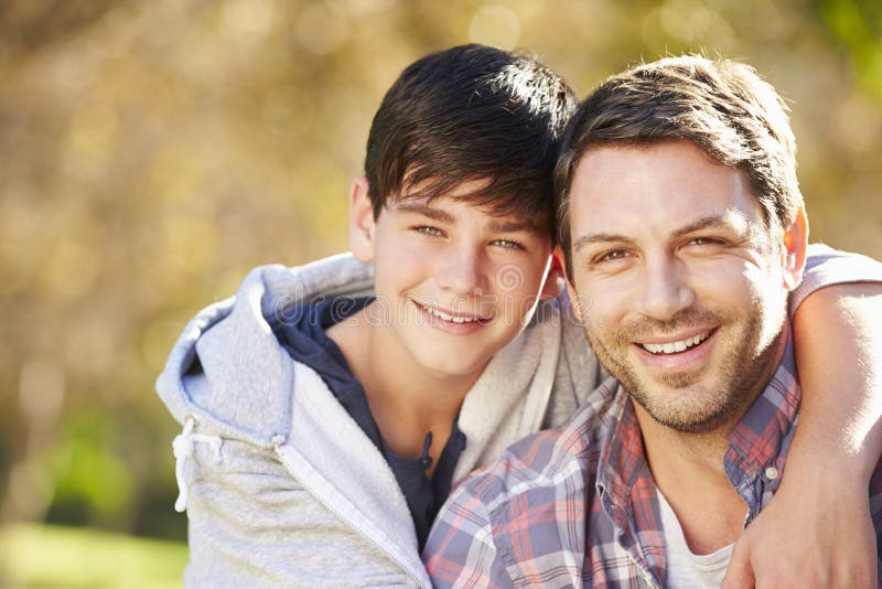 Portrait Of Father And Son In Countryside With Arm Around Shoulder Smiling. Portrait Of Father And Son In Countryside With Arm Around Shoulder Smiling