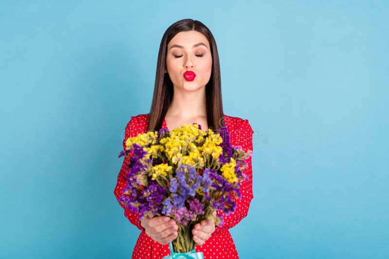 Portrait of attractive glamorous dreamy flirty girl giving you blossom flowers sending air kiss isolated over bright blue color background. Portrait of attractive glamorous dreamy flirty girl giving you blossom flowers sending air kiss isolated over bright blue color background.