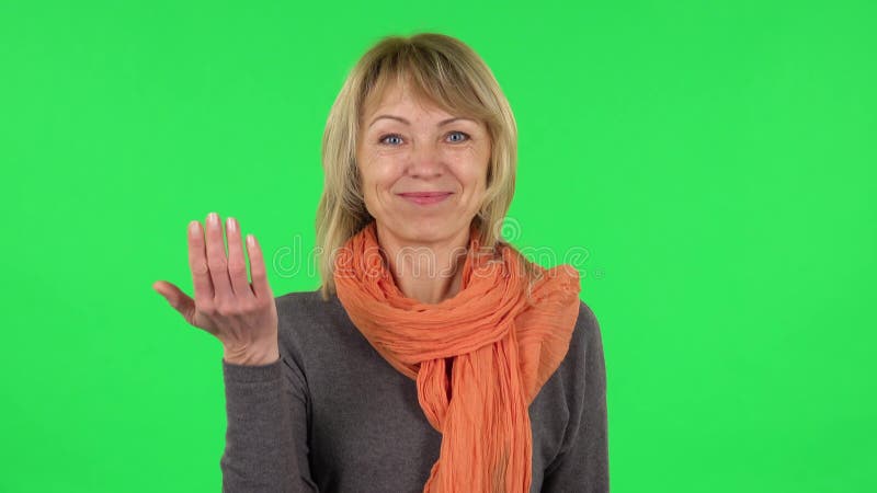 Портрет средней достигшей возраста белокурой женщины машет рукой и говорит о том, что этот жест приходи сюда. Зеленый экран видеоматериал