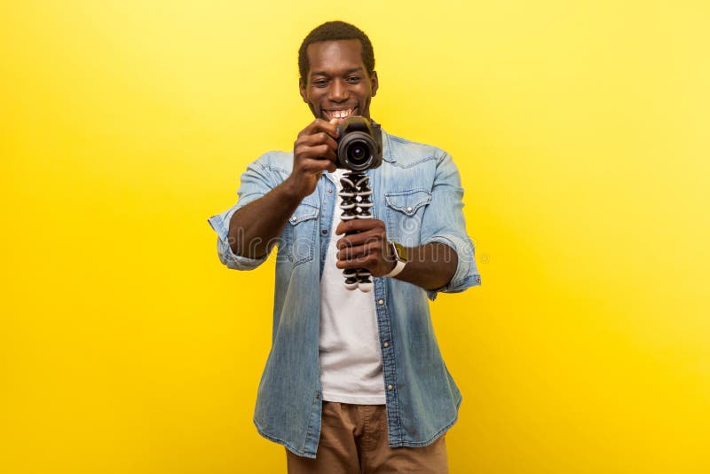 Портрет счастливого фотографа с профессиональной цифровой dslr камерой крытая студия-студия, изолированная на желтом фоне стоковое изображение rf Портрет счастливого фотографа с профессиональной цифровой dslr камерой крытая студия-студия, изолированная на желтом фоне стоковое изображение rf