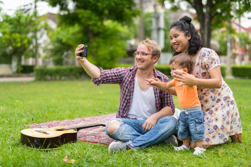 Портрет счастливой мульти-этнической семьи принимая selfie совместно outdoors стоковые фотографии rf Портрет счастливой мульти-этнической семьи принимая selfie совместно outdoors стоковые фотографии rf
