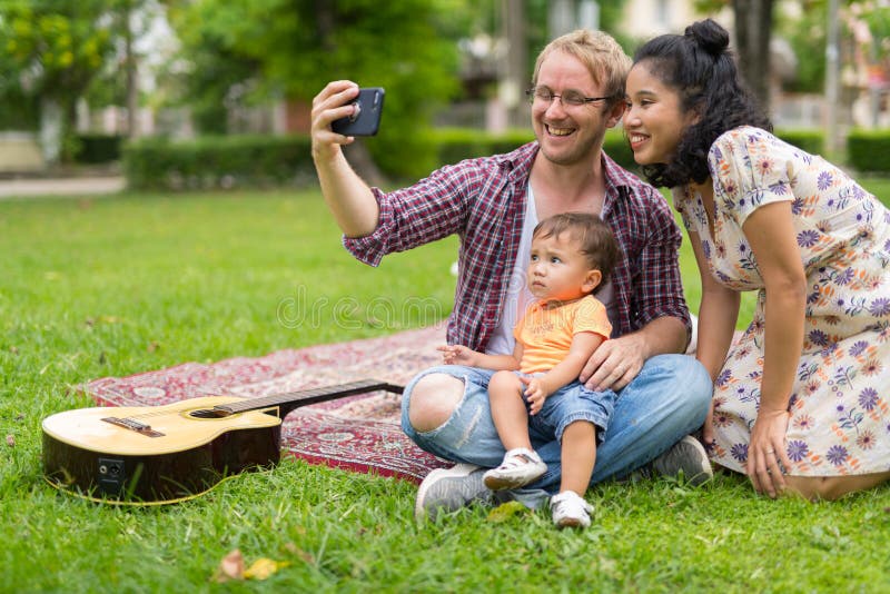 Портрет счастливой мульти-этнической семьи принимая selfie совместно outdoors стоковые фотографии rf Портрет счастливой мульти-этнической семьи принимая selfie совместно outdoors стоковые фотографии rf