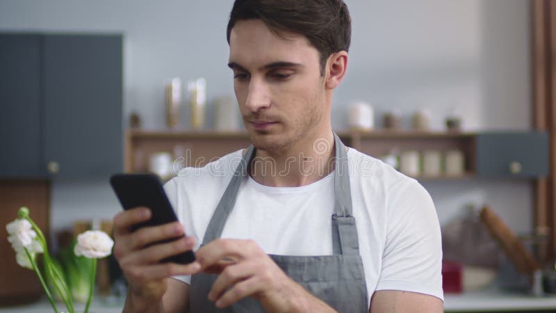 Портрет улыбающегося человека повара, рецепт на кухне мобильных телефонов дома.