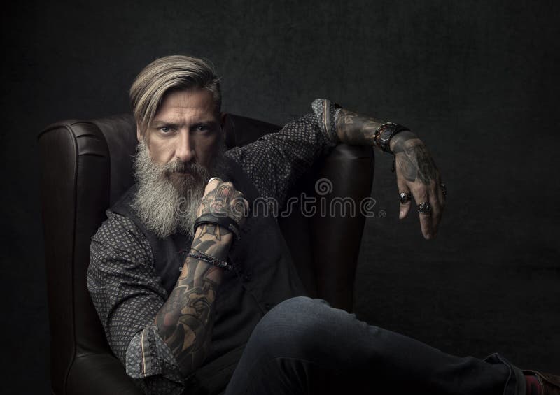 Portrait of a cool bearded businessman, who is sitting on an armchair. Portrait of a cool bearded businessman, who is sitting on an armchair.