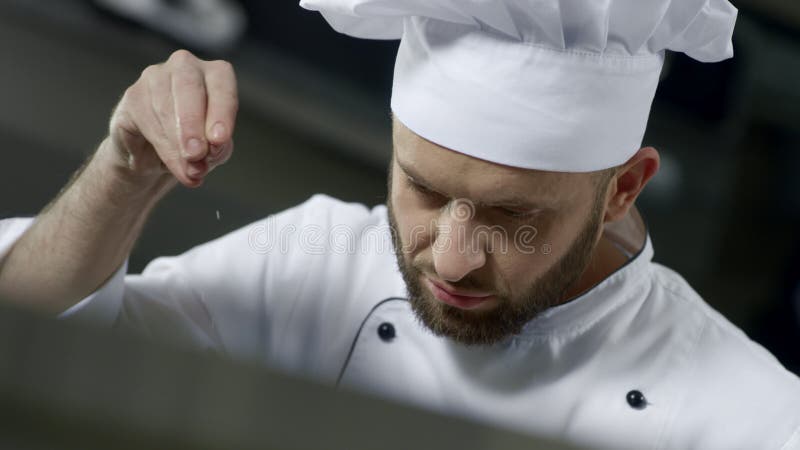 Портрет шеф-повара соля еду на кухне Шеф-повар варя еду в замедленном движении