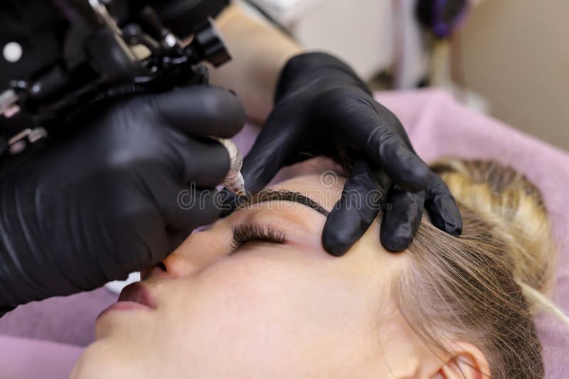 Постоянный макияж Постоянный татуировать бровей Cosmetologist прикладывая перманентность составляет на татуировке брови бровей стоковые фотографии rf Постоянный макияж Постоянный татуировать бровей Cosmetologist прикладывая перманентность составляет на татуировке брови бровей стоковые фотографии rf