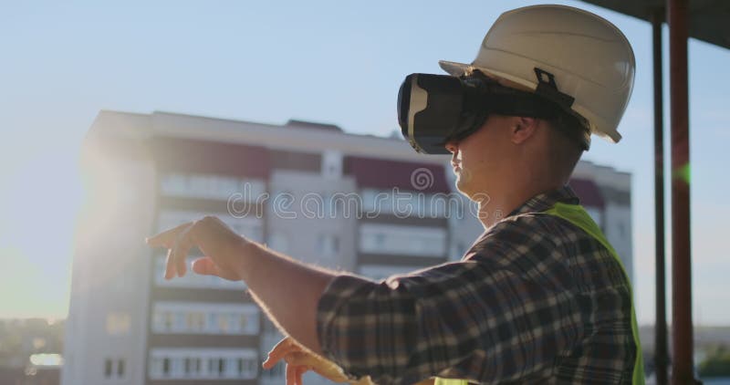 Построитель инженера на крыше здания на заходе солнца стоит в стеклах vr и двигает его руки используя интерфейс акции видеоматериалы