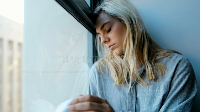 Потревоженная женщина сидя около окна 4k