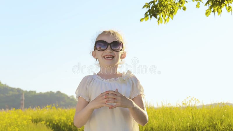 Прелестная маленькая девочка кладет дальше пару солнечных очков и улыбок