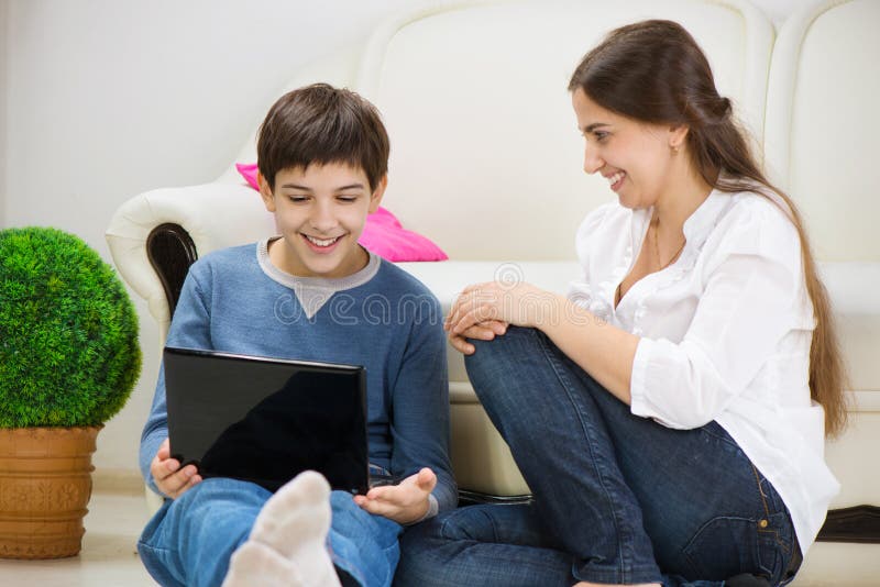 Teen son with young mother with laptop at home. Teen son with young mother with laptop at home