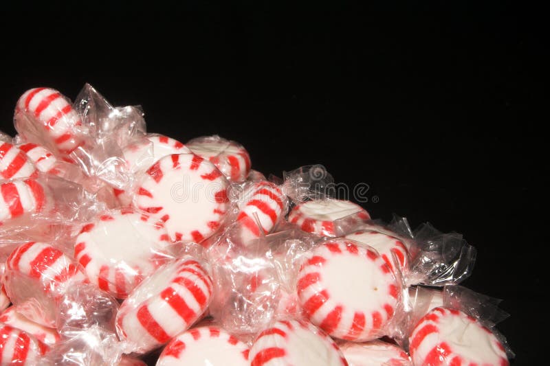 A background of peppermint candies on a black background. A background of peppermint candies on a black background.