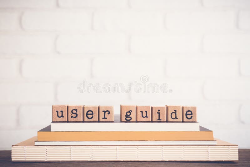 The word User guide, text on wooden cubes on top of books. Background copy space, vintage minimal. Concepts of manual or technical communication document to give assistance about using system. The word User guide, text on wooden cubes on top of books. Background copy space, vintage minimal. Concepts of manual or technical communication document to give assistance about using system.