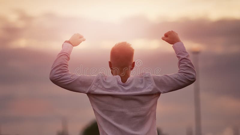 Предпосылка неба захода солнца победы показа руки привлекательного мышечного человека поднимая сильная празднуя изумляя