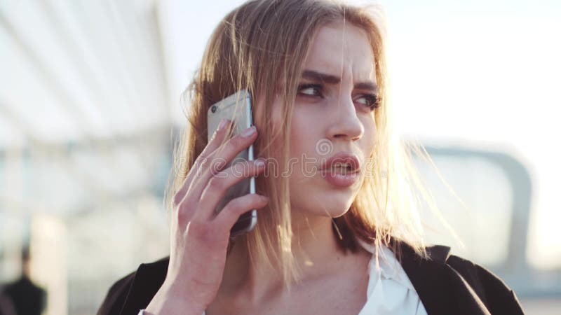 Привлекательная занятая европейская коммерсантка говорит на ее телефоне, проверяет время, и касается ее волосам Официально обмунд
