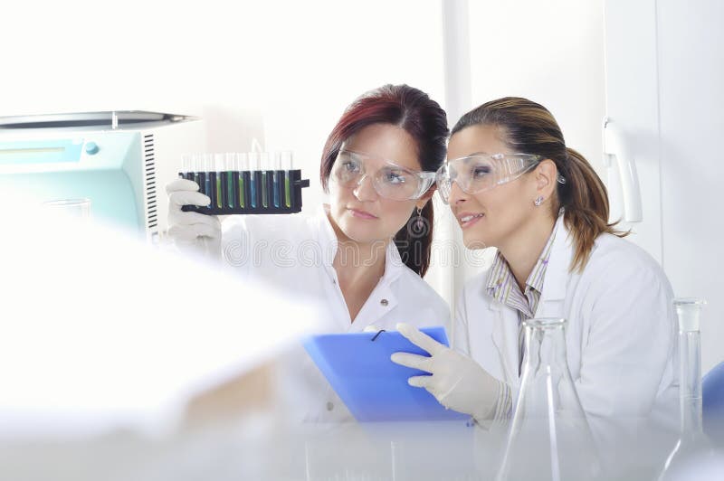 Привлекательные ученые студентов PhD детенышей наблюдая цветом переносят после destillation решения в химической лаборатории стоковая фотография rf Привлекательные ученые студентов PhD детенышей наблюдая цветом переносят после destillation решения в химической лаборатории стоковая фотография rf