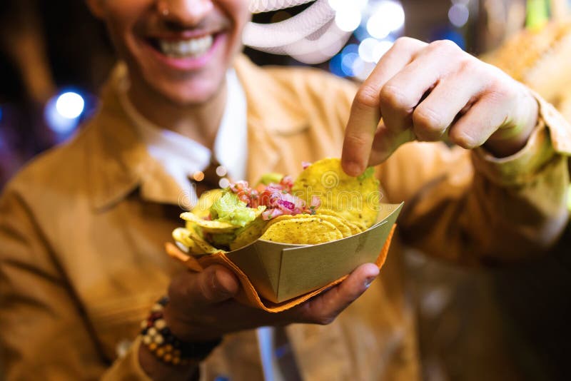 Привлекательное посещение молодого человека ест рынок и nachos еды в улице стоковое фото