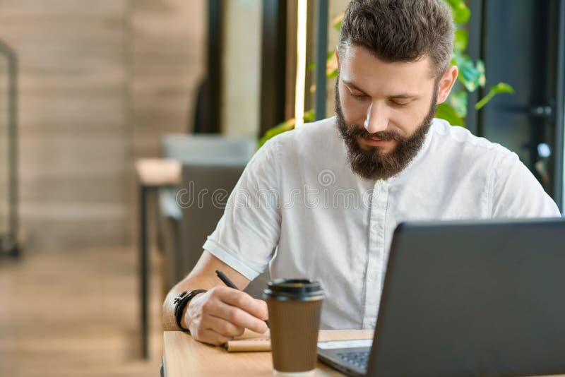Примечания сочинительства битника Bearder пока работающ с компьтер-книжкой, выпивая кофе стоковые фотографии rf