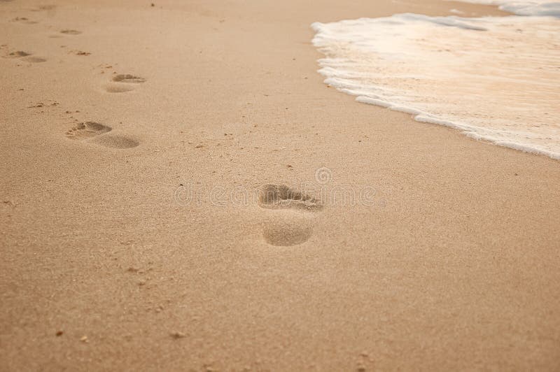 Natural background for text and sand and sea waves. Footprints in the sand from the legs go into the distance. Summer, sea, sunrise. Natural background for text and sand and sea waves. Footprints in the sand from the legs go into the distance. Summer, sea, sunrise.