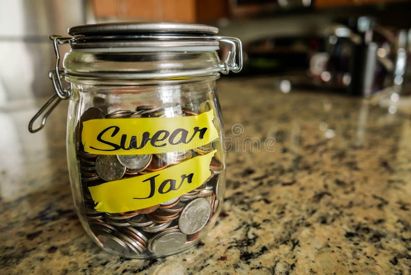 A clear glass jar filed with coins and bills, saving money. The words Swear Jar written on the outside. A clear glass jar filed with coins and bills, saving money. The words Swear Jar written on the outside.