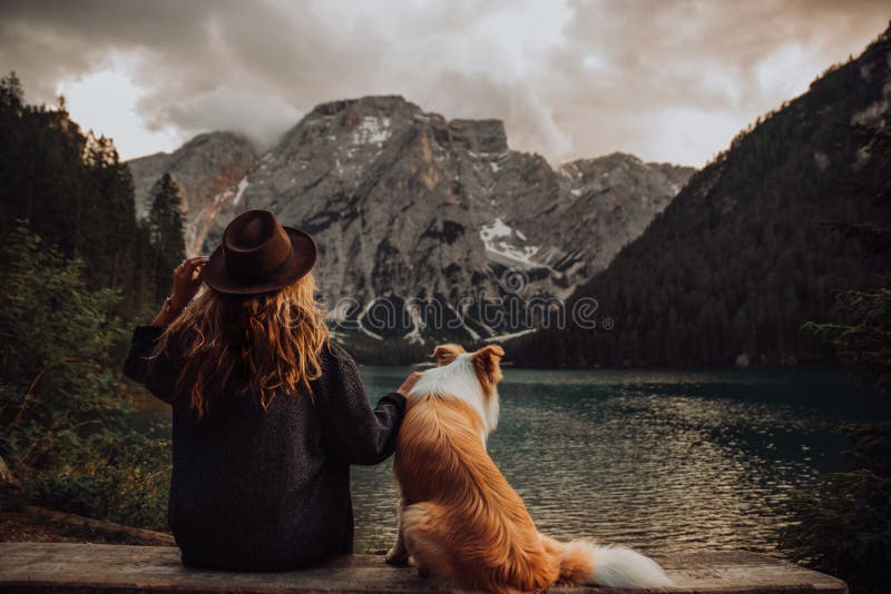 Приятельство между ребенком и собакой сидя около озера Lago di Braies стоковые изображения rf Приятельство между ребенком и собакой сидя около озера Lago di Braies стоковые изображения rf