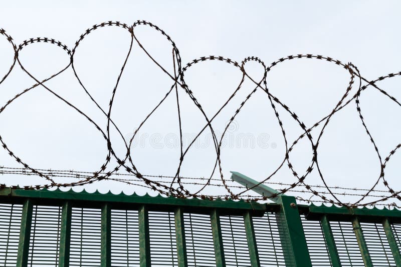 Провод бритвы na górze зеленой загородки защищая французский паромный терминал стоковое изображение rf Провод бритвы na górze зеленой загородки защищая французский паромный терминал стоковое изображение rf