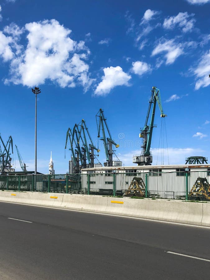 Промышленная верфь для кораблей в порте с большими кранами утюга для нагружать и разгружать грузы около дороги стоковая фотография Промышленная верфь для кораблей в порте с большими кранами утюга для нагружать и разгружать грузы около дороги стоковая фотография
