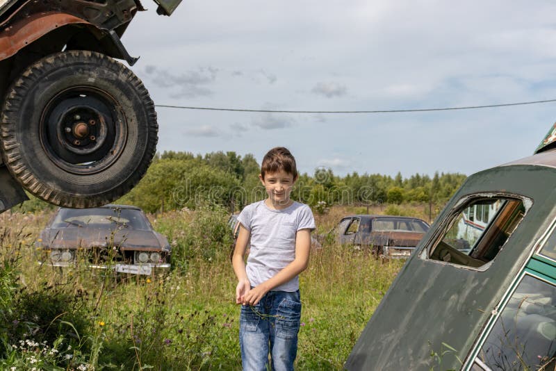 Проницательный кавказский подросток, стоящий на траве в пригороде в летний день с серьезным выражением лица, на ретро-машине стоковая фотография