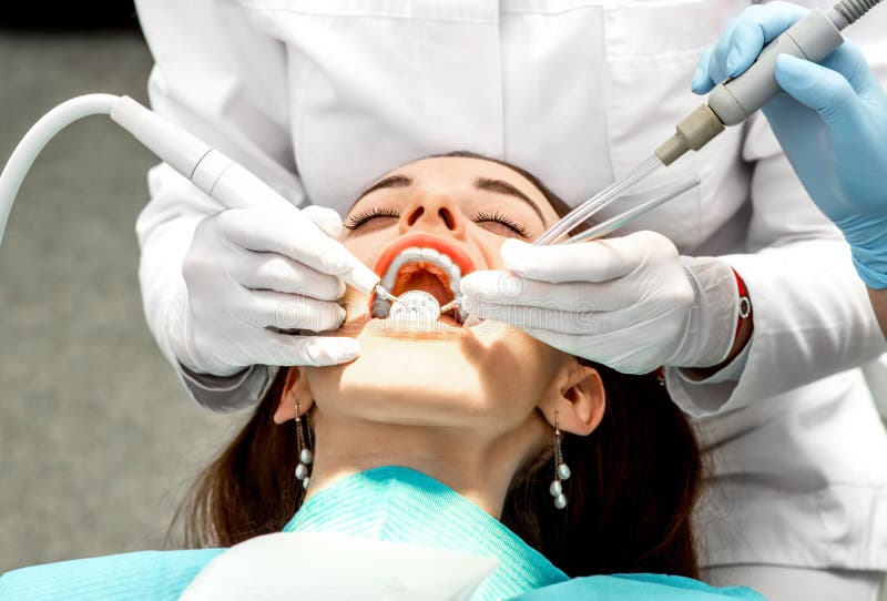 Dentist making professional teeth cleaning female young patient at the dental office. Dentist making professional teeth cleaning female young patient at the dental office