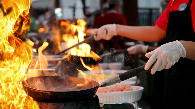 Профессиональный шеф-повар в коммерчески кухне варя стиль Flambe стоковые изображения Профессиональный шеф-повар в коммерчески кухне варя стиль Flambe стоковые изображения