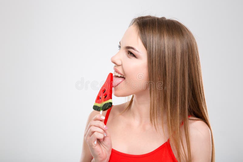 Профиль красивой девушки лижа арбуз сформировал lollypop стоковая фотография rf Профиль красивой девушки лижа арбуз сформировал lollypop стоковая фотография rf