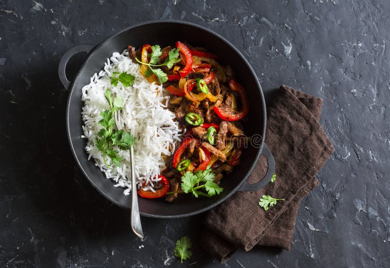 Пряная говядина с овощами и рисом в skillet литого железа на темной предпосылке, взгляд сверху стоковые изображения rf Пряная говядина с овощами и рисом в skillet литого железа на темной предпосылке, взгляд сверху стоковые изображения rf