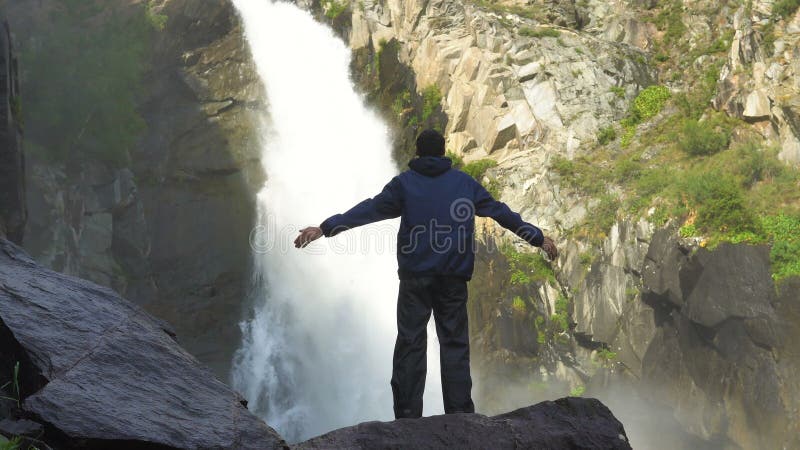 Путешественник стоит перед водопадом