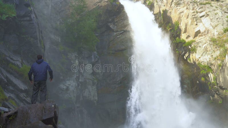 Путешественник стоит рядом с водопадом