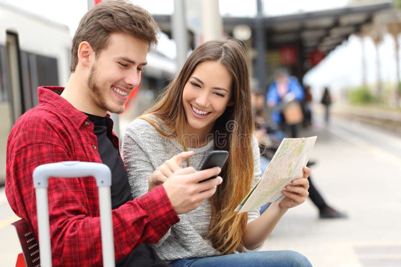 Tourists travelers consulting gps and guide from a smart phone in a train station. Tourists travelers consulting gps and guide from a smart phone in a train station