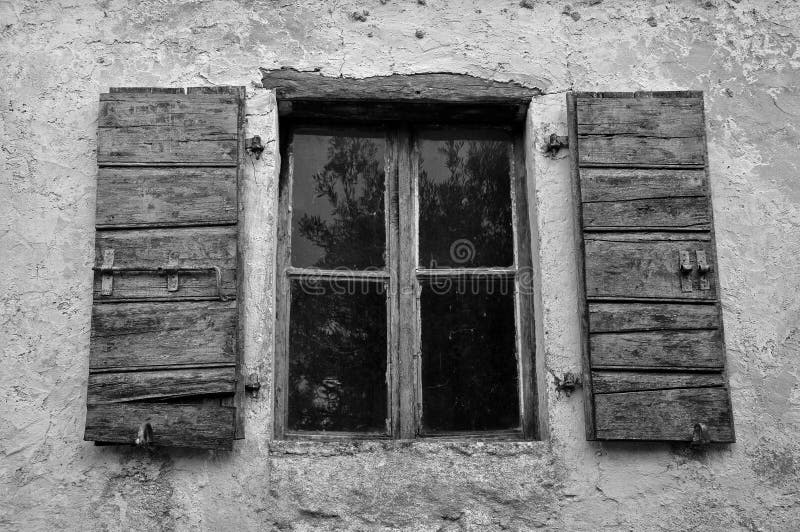 Dusty window wooden shutters and textured wall of abandoned house. Black and white. Dusty window wooden shutters and textured wall of abandoned house. Black and white.