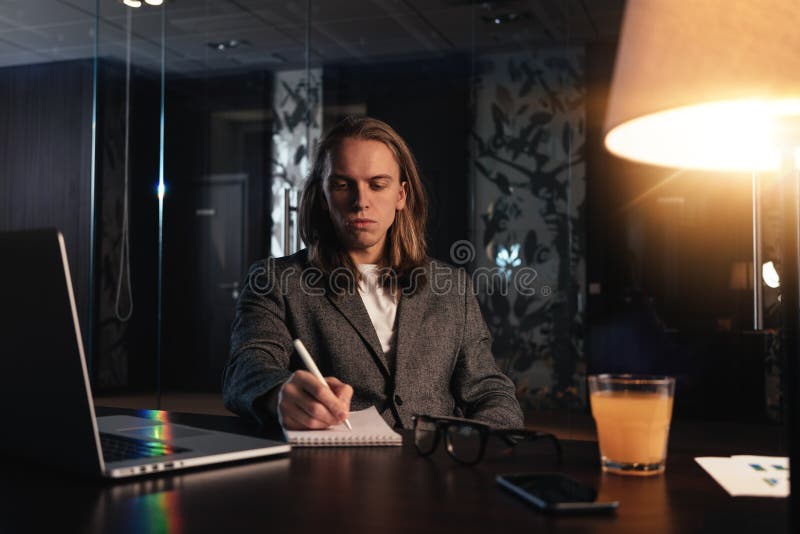 Работа отростчатая на современном офисе ночи Молодая работа сотрудника в coworking студии Бизнесмен использует современный компью стоковые фото