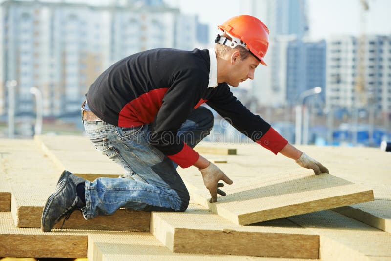 Работник Roofer устанавливая материал изоляции крыши стоковое изображение Работник Roofer устанавливая материал изоляции крыши стоковое изображение